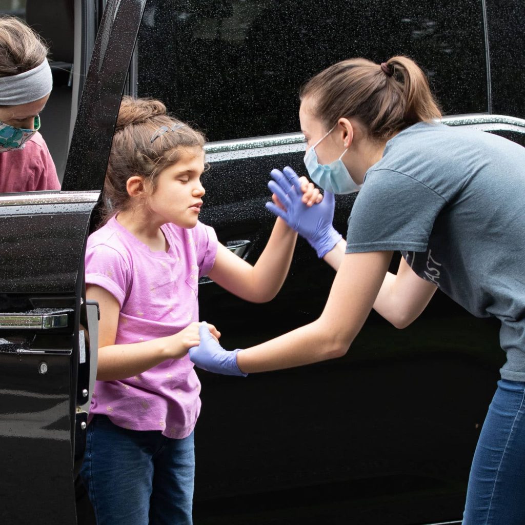 DeafBlind Intervener supporting a DeafBlind Child out of a car